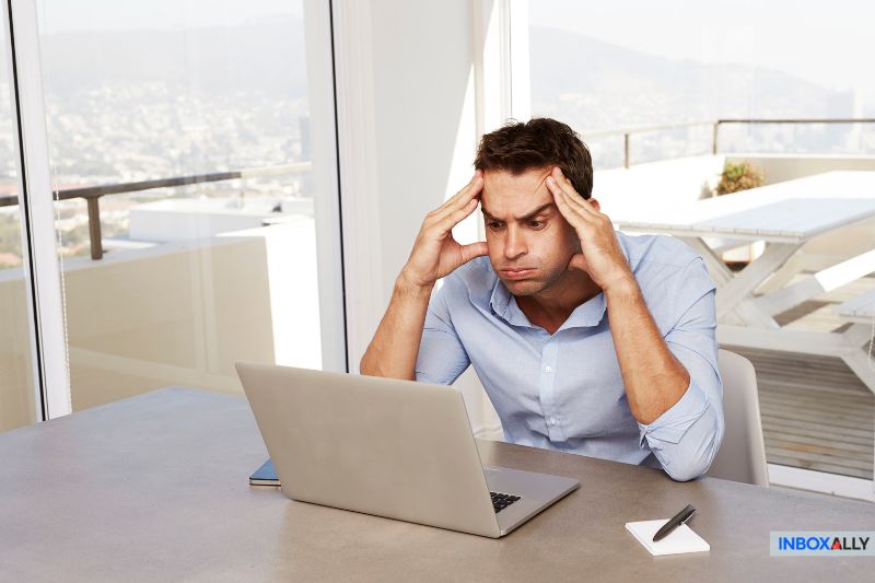 A frustrated man staring at his laptop, trying to resolve the issue of "my emails are bouncing" quickly.