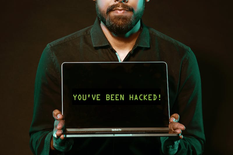 Man holding a laptop with a message saying "you've been hacked"