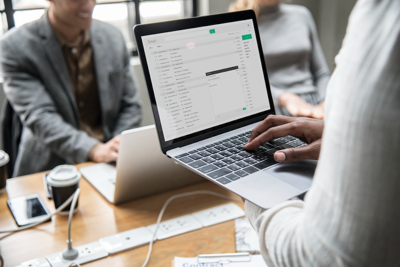 A person holds a laptop with an email application open, addressing the need for follow-up emails