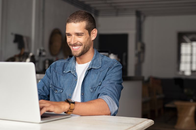 Homem digitando em um laptop em uma mesa, trabalhando para limpar sua lista de e-mails.