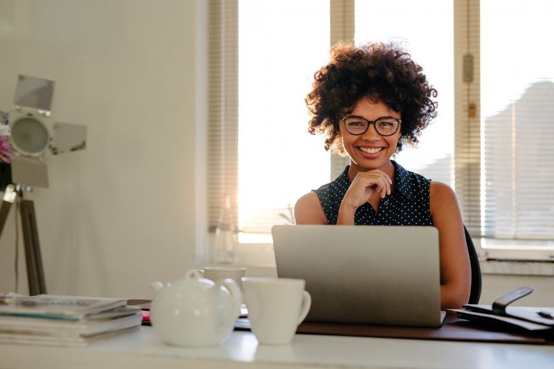 Uma pessoa em uma mesa com um laptop, provavelmente satisfeita após concluir a limpeza de uma lista de e-mails.