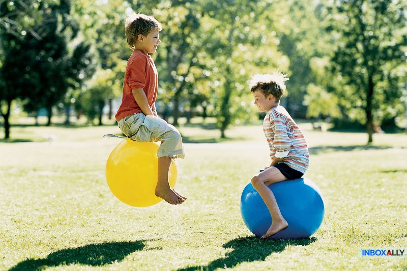 Two children bouncing on inflatable balls, metaphorically illustrating 'message blocked Gmail' struggles and email deliverability challenges