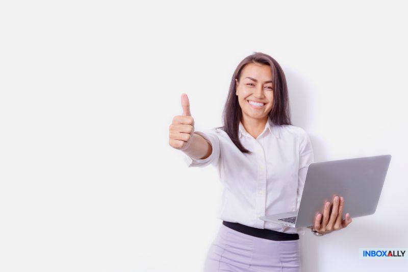 Smiling woman giving thumbs up with laptop, symbolizing a successful fix for 'message blocked Gmail' email delivery issues.