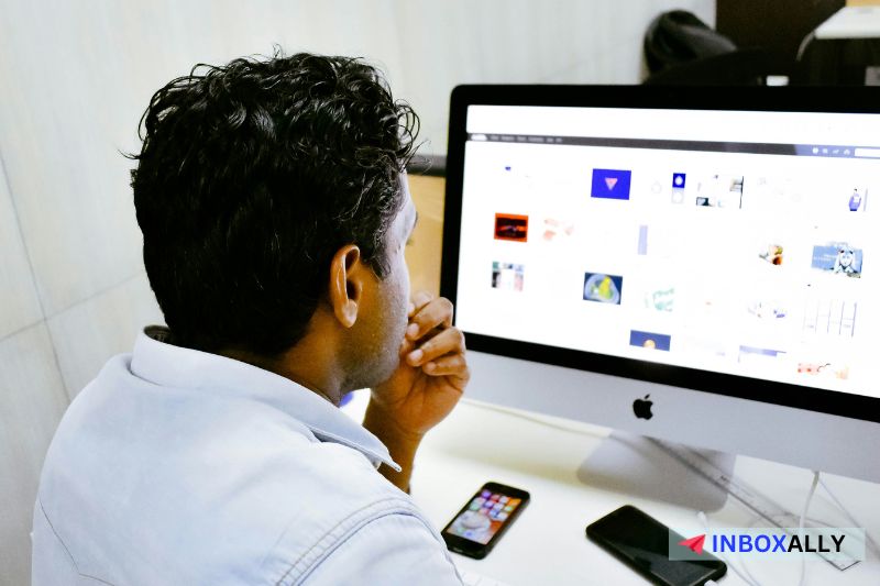 A person t sits at a desk, looking at a computer monitor possibly preparing for the mass email campaign.