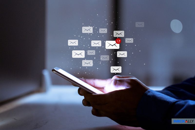Uma pessoa segura um smartphone com vários ícones de e-mail flutuando acima dele, indicando notificações, incluindo um com o número 12 - uma prova de seu envolvimento ativo em estratégias de marketing por e-mail.