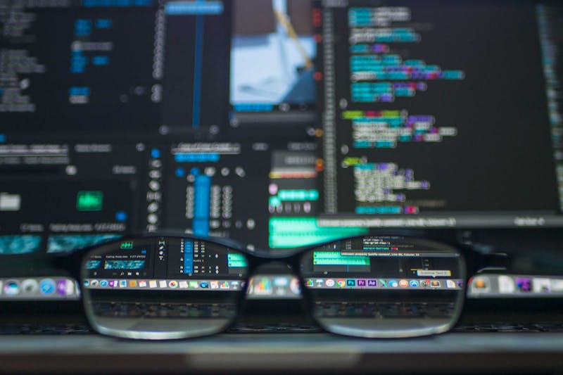 Close-up of glasses resting on a laptop keyboard, with computer code displayed on the screen in the background, reflecting the psychology of sender reputation.