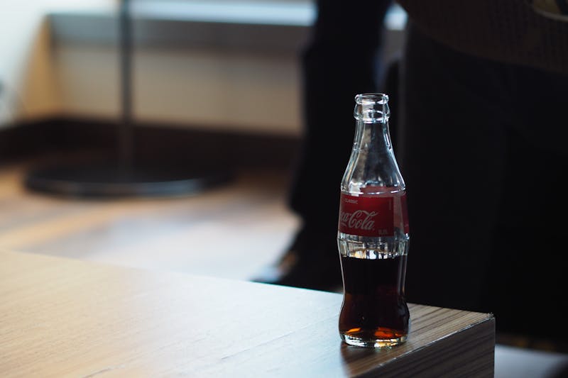 A Coca-Cola bottle, a symbol of trust, sits casually on the edge of a wooden table showcasing building trust with your audience.