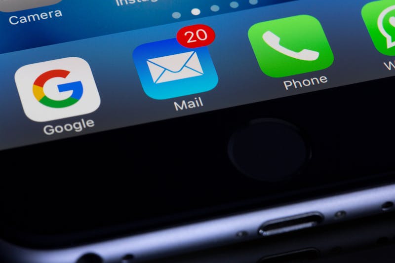 Close-up of a smartphone screen reveals app icons for Google, Mail with 20 unread notifications crowding the inbox, Phone, and WhatsApp.