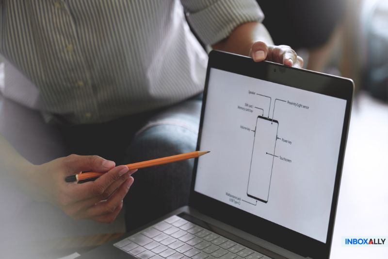 A person points at a laptop screen with a pencil, displaying a diagram of a smartphone while discussing an Inbox Placement strategy.