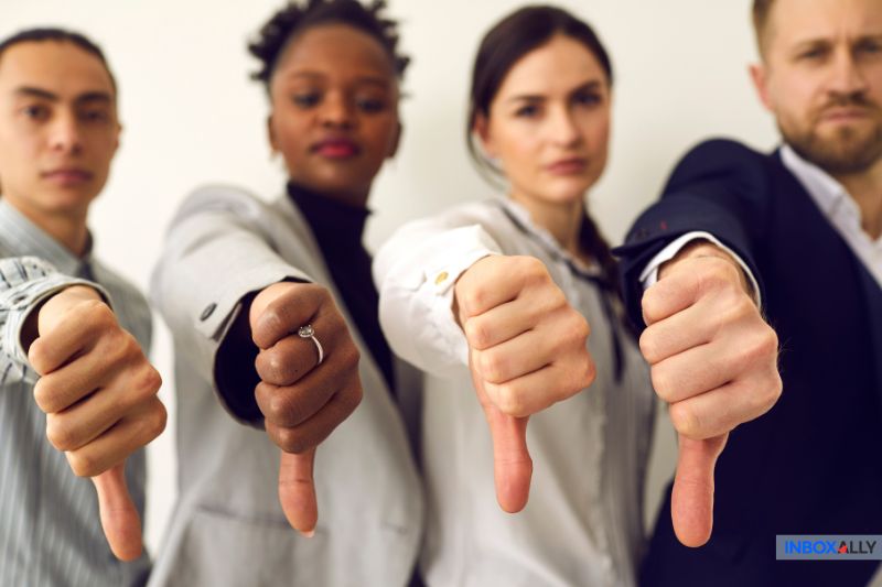 Four professionals giving thumbs-down, symbolizing disapproval and emphasising the negative impact of poor email deliverability on businesses.