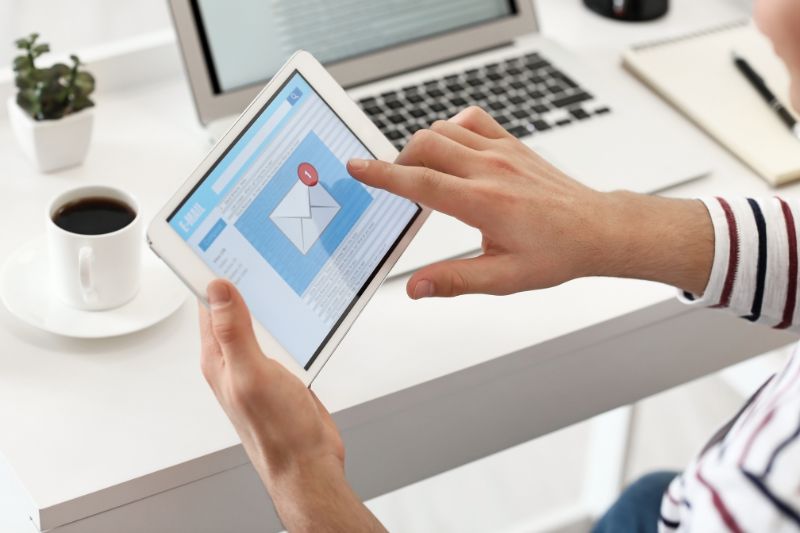 A person is effectively reading an email on a tablet at a desk, surrounded by a laptop, coffee cup, and notebook. It looks like they are preparing to tackle the challenges of 2025's fast-paced digital world.