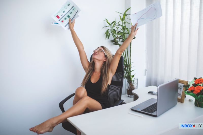 A businesswoman celebrates success with charts in hand, symbolising productivity and growth using Keap alternatives