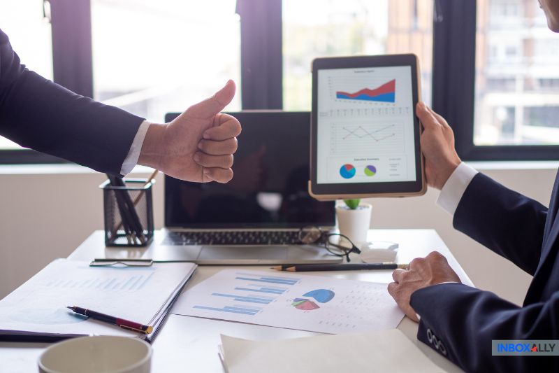 A business team analysing email campaign metrics with graphs on a tablet, illustrating the concept of the "open rate formula."