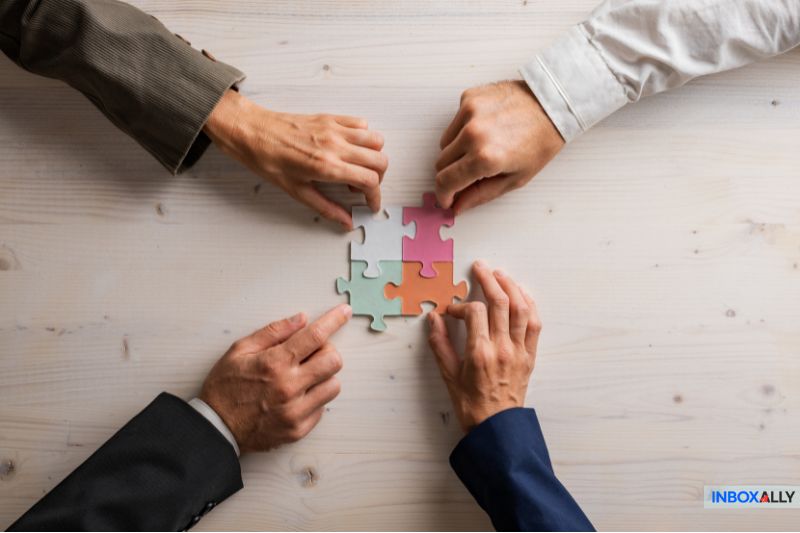 Mail merge advantages visualized through teamwork, as four hands connect puzzle pieces